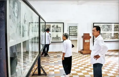  ?? ELI MEIXLER ?? People look at portraits of S-21 inmates at the Tuol Sleng Genocide Museum in Phnom Penh in 2014.