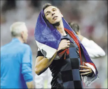  ?? Frank Augstein The Associated Press ?? Croatia forward Mario Mandzukic drapes himself in his nation’s flag after Vatreni beat England on Wednesday to advance to the World Cup final against France.