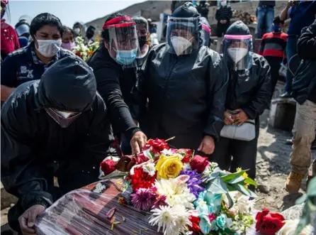  ?? AFP ?? Familiares de una víctima de covid-19 lloran durante el funeral, en un cementerio de Comas, periferia norte de Lima. Perú ocupa el tercer puesto en casos y muertes en Latinoamér­ica.