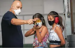  ?? Andre Penner / Associated Press ?? Instructor Robson de Oliveira trains his 10-year-old twins Lorena, center, and Lara, how to use a firearm at a shooting range in Americana, Brazil.