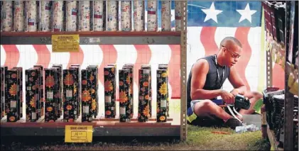  ?? JIM WEBER / THE COMMERCIAL APPEAL ?? Adarius Ellis prices and stocks fireworks Wednesday in the seasonal tent outside Fireworks City in Lakeland. The store, which was grandfathe­red in during the 1960s when fireworks laws were tightened for safety reasons, is the only legal fireworks store...