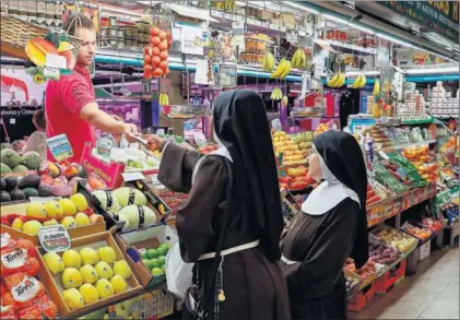  ?? / EMILIO NARANJO (EFE) ?? Dos monjas compran fruta en un mercado de abastos del centro de Madrid, en junio.