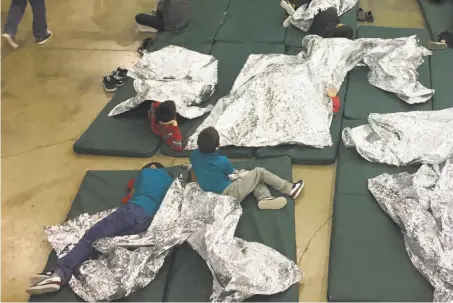  ?? U.S. Customs and Border Protection ?? People taken into custody related to cases of illegal entry into the U.S. rest Sunday in a holding facility in McAllen, Texas.