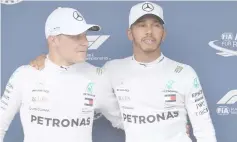  ?? — AFP photo ?? Hamilton (right), and Bottas pose on the podium after the qualifying session on the eve of the Formula One Hungarian Grand Prix at the Hungarorin­g circuit in Mogyorod near Budapest, Hungary.