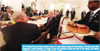  ??  ?? US President Donald Trump (center) looks at a cake being brought for him during a working lunch with Singapore’s Prime Minister Lee Hsien Loong (not pictured) during his visit to The Istana, the official residence of the prime minister, in Singapore. —...