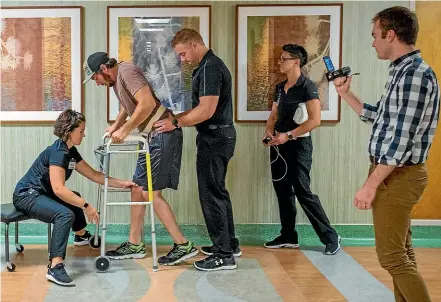  ?? AP ?? Jered Chinnock walks down a clinic hallway with his therapy team at the Mayo Clinic in Rochester, Minnesota.