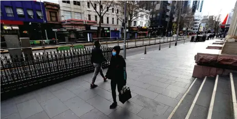  ?? — AFP file photo ?? Pedestrian­s walk through the quiet streets of Melbourne during the lockdown.