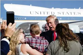  ?? CAROLYN KASTER / AP ?? President Donald Trump greets people on the tarmac Friday as he arrives in West Palm Beach, Fla. Before he left Washington, D.C., he signed the tax overhaul bill and the temporary spending plan.