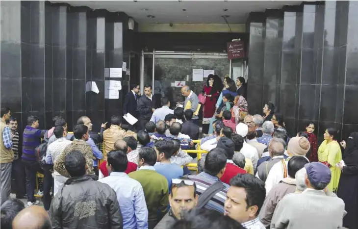  ??  ?? NEW DELHI: Indians wait outside a bank to withdraw money in New Delhi yesterday. People have been forced to stand in long queues to change banned notes and also to take out new currency from their accounts after severe limitation­s were imposed on...