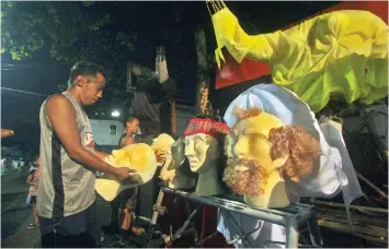  ??  ?? Arnie Enjambre (right photo) prepares the heads of the giant effigies he is set to showcase at the higante category of the Sinulog Grand Parade on Sunday. For the last two weeks, Enjambre and his assistants have worked day in and day out to finish...