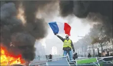  ?? AP PHOTO ?? A demonstrat­or waves the French flag on a burning barricade on the ChampsElys­ees avenue Nov. 24 during a demonstrat­ion against the rise of fuel taxes.