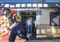  ?? Brian van der Brug Los Angeles Times ?? A FAN runs to board a bus from a Metro stop to SoFi Stadium for a Rams game. Improving transporta­tion to and from the stadium is a priority.