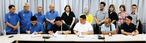  ?? ?? Gan (left) and Ng (centre) signing the agreement at POIC Lahad Datu, witnessed by Yong.