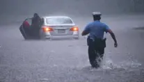  ?? MATT SLOCUM/ASSOCIATED PRESS ?? A police officer rushes to help a motorist stranded by floodwater­s Tuesday in Philadelph­ia. Isaias spawned tornadoes and dumped rain during an inland march up the East Coast after making landfall as a hurricane along the North Carolina coast.
