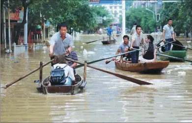  ?? LONG LINZHI / FOR CHINA DAILY ?? Aided by boatmen, residents make their way around streets flooded by heavy rain in Rongshui Miao autonomous county in the Guangxi Zhuang autonomous region on Sunday.