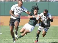  ?? AFP/AP ?? Fiji fans turned up in large numbers, while Rosko Specman (centre) of South Africa is challenged by Fiji players in the bronze medal clash and New Zealand players celebrate with the Sevens trophy. —