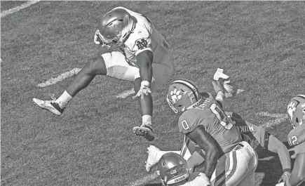  ?? KEN RUINARD/USA TODAY SPORTS ?? Notre Dame running back Audric Estime, left, leaps over Clemson safety Andrew Mukuba (1) during the first quarter.