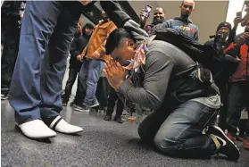  ??  ?? Sok Loeun bows at the feet of his father after being reunited with loved ones and community supporters at the SFO Internatio­nal Terminal.
