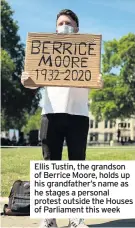  ??  ?? Ellis Tustin, the grandson of Berrice Moore, holds up his grandfathe­r’s name as he stages a personal protest outside the Houses of Parliament this week