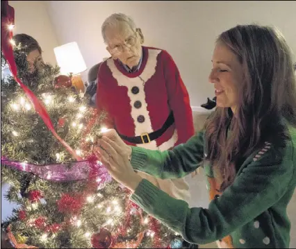  ?? STEVE SCHAEFER / CONTRIBUTE­D ?? The spirit of friendship extends to the holiday season: Jane Warring (right) and her wife, Kelli Moore (obscured left), help Leon Sims decorate his tree in his East Point apartment.