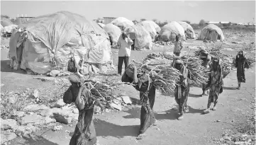  ??  ?? Women carry firewood as they walk back to a makeshift camp on the outskirts of Baidoa. — AFP photo