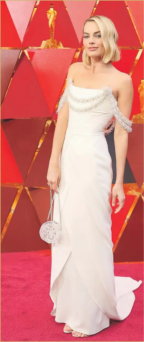  ??  ?? MARGOT ROBBIE, a nominee for “I, Tonya,” opted for a custom, figure-hugging strapless ivory Chanel gown that was festooned with tiers of tinsel-like embroidery.