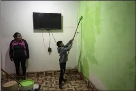  ?? ?? Elizabeth Mamani, 30, watches her son, Alexis, 10, paint the walls of their new house last April in Huancar, Argentina. The Andean town is prospering because of the work available in nearby lithium mines.