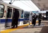  ?? CP PHOTO JASON FRANSON ?? People board the LRT at the Century Park LRT station in Edmonton, on Friday. A Black Muslim woman was recently threatened and subjected to racial slurs at the station.