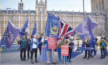  ?? — AFP ?? Pro-european Union, anti-brexit demonstrat­ors hold placards and wave Union and EU flags as they protest outside of the Houses of Parliament in London on Wednesday.