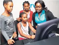  ??  ?? From left: Latoya Newell-Irving, FLOW retail sales store supervisor, shows a group of participan­ts from the JA Biztown Tech Camp how to use the computer during a visit to the FLOW corporate store.