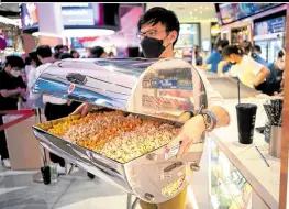  ?? —PHOTOS BY REUTERS ?? IN STYLE A man uses a food warmer to bring the popcorn he bought for 199 baht ($5.60).