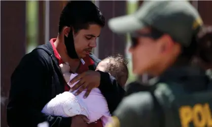  ??  ?? A man seeking asylum holds his infant daughter as they wait to be transporte­d by the US Border Patrol after crossing from Mexico into California on 19 April. Photograph: Jim Urquhart/Reuters