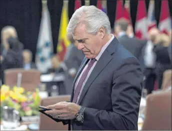  ?? CP PHOTO ?? Newfoundla­nd and Labrador Premier Dwight Ball checks his mobile device as he waits for the First Ministers Meeting to begin in Ottawa.