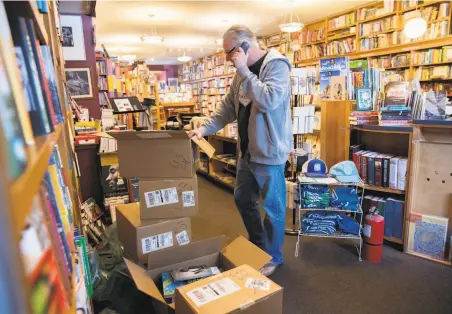  ?? Santiago Mejia / The Chronicle ?? Eric Whittingto­n takes a phone call from a customer for a book request March 17 at Bird & Beckett Books & Records in San Francisco. Bookstores and certain other businesses will be permitted to have curbside pickup service beginning Friday.