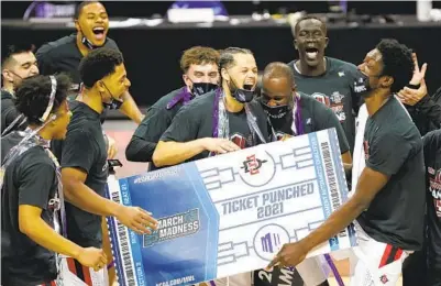  ?? K.C. ALFRED U-T ?? San Diego State University basketball players celebrate Saturday in Las Vegas after beating Utah State 68-57 to win the Mountain West tournament and secure the champion’s automatic berth into the NCAA Tournament.