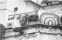  ?? Alessandra Tarantino / Associated Press ?? A man in Rome unfolds an Italian flag as he stands next to a banner reading, “Everything will be all right.”