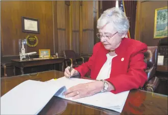  ?? Hal Yeager / Associated Press ?? This photograph released by the state shows Alabama Gov. Kay Ivey signing a bill that virtually outlaws abortion in the state on Wednesday in Montgomery, Ala.
