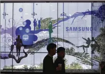  ?? AHN YOUNG-JOON / ASSOCIATED PRESS ?? Two men walk past Samsung Electronic­s’ store in Seoul, South Korea, on Wednesday. Asia’s fourth-largest economy is being kept humming by soaring chip demand.