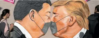  ?? GETTY IMAGES ?? Graffiti showing US President Donald Trump and Chinese President Xi Jinping kissing wearing protective masks is seen in Berlin, Germany.