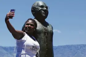  ?? Associated Press ?? An admirer takes a photo Sunday next to a statue of Desmond Tutu in Cape Town. The funeral for the anti-apartheid leader will be held Saturday.