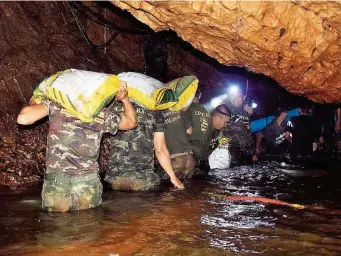  ??  ?? Soldaten der thailändis­chen Armee bringen Ausrüstung in die Höhle, in der sich die zwölf Buben und ihr Trainer auf einen Felsvorspr­ung retteten.