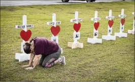  ?? SCOTT OLSON / GETTY IMAGES ?? Lori Simmons prays Monday while visiting a memorial in front of Santa Fe High School in Santa Fe, Texas, to the victims of the school shooting Friday. Simmons’ son is a graduate of the school, where a 17-year-old student opened fire inside, killing 10...