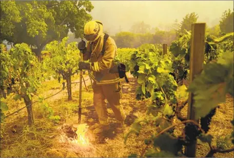  ?? Photog r aphs by Kent Nishimura Los Angeles Times ?? A SACRAMENTO f iref ighter takes part in an operation near a property as crews try to contain the Glass f ire on Sunday in Napa County.