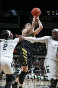  ?? AL GOLDIS — THE ASSOCIATED PRESS ?? Oregon’s Sabrina Ionescu, center, shoots between Michigan State’s Mardrekia Cook, left, and Nia Hollie, right, during the first half Sunday’s game in East Lansing, Mich. Michigan State won 88-82.