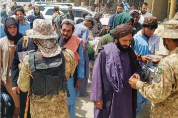  ?? — AFP ?? Pakistani soldiers check the documents of stranded Afghan nationals wanting to return to Afghanista­n at the Pakistan-Afghanista­n border crossing point in Chaman on Sunday.