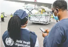  ?? JEAN BIZIMANA/REUTERS FILES ?? World Health Organizati­on officials watch the arrival of coronaviru­s vaccines at Kigali airport in Rwanda in March.