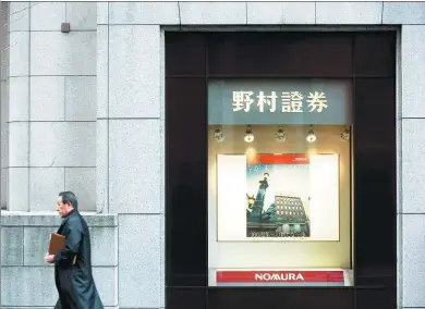  ?? BLOOMBERG ?? A man walks past the headquarte­rs of Nomura Securities Co, a unit of Nomura Holdings Inc, in Tokyo.