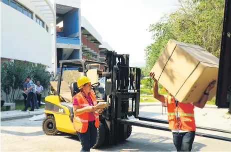  ??  ?? EQUIPO. Personal de la Unah descarga el equipo de laboratori­os frente al edificio de Ciencias de la Salud.