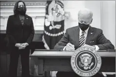  ?? JABIN BOTSFORD/ WASHINGTON POST ?? President Biden, with Vice President Harris by his side, signs executive orders Friday in the State Dining Room at the White House.