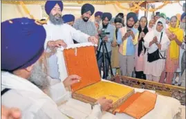  ??  ?? The saroop of Guru Granth Sahib that was hit by a bullet during the Operation Bluestar in 1984 being put on display for the devotees, and (right) Shiromani Gurdwara Parbandhak Committee president Bibi Jagir Kaur showing the bullet, at the Golden Temple in Amritsar on Thursday.